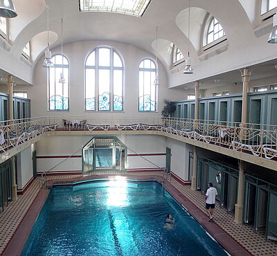 Mann mit weißen T-Shirt steht neben einem Pool im alten Stadtbad Augsburg
